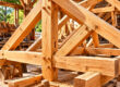 Charpente traditionnelle en bois en cours d'assemblage dans un atelier de charpentier avec fermes et chevilles en bois.